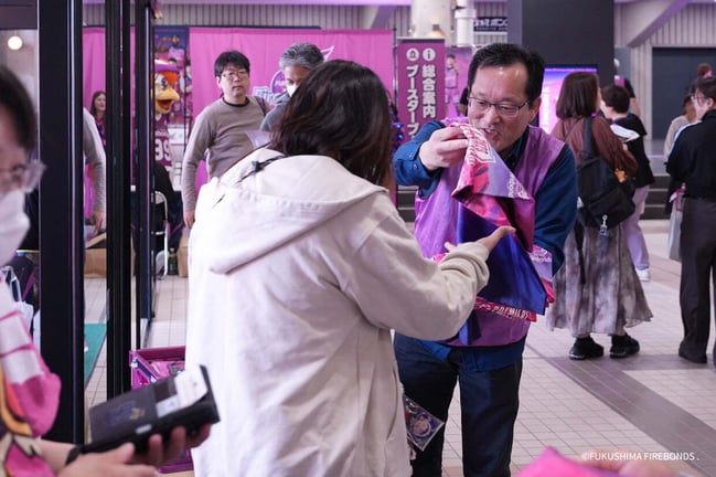 福島ファイヤーボンズの会場内で、来場者にグッズを手渡すスタッフ